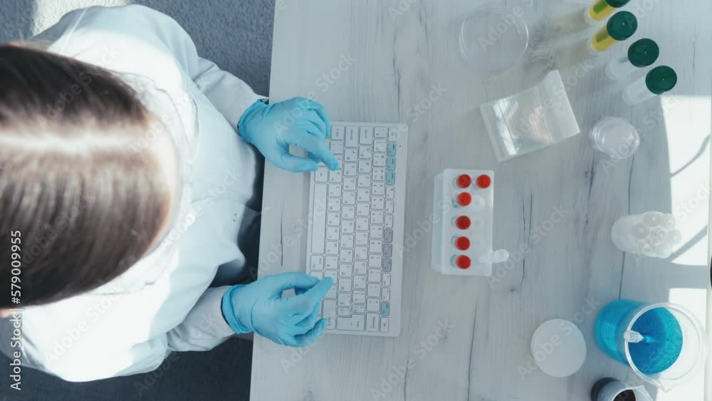 Poster a female researcher sits at a workplace in a laboratory, behind a personal computer monitor. against