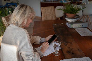 femme d'âge mûr travaillant à domicile avec son telephone portable