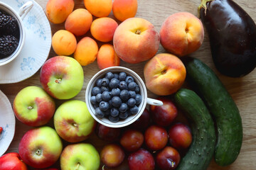 Berries in vintage porcelain dishes, other healthy fruit and vegetable on wooden table. Top view.