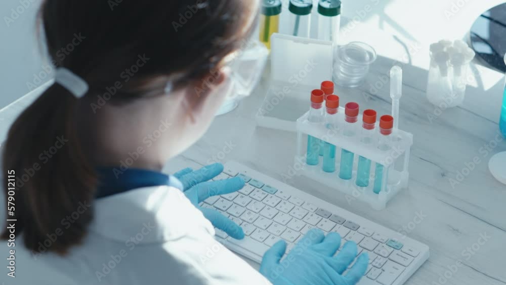 Poster a female researcher sits at a workplace in a laboratory, behind a personal computer monitor. against