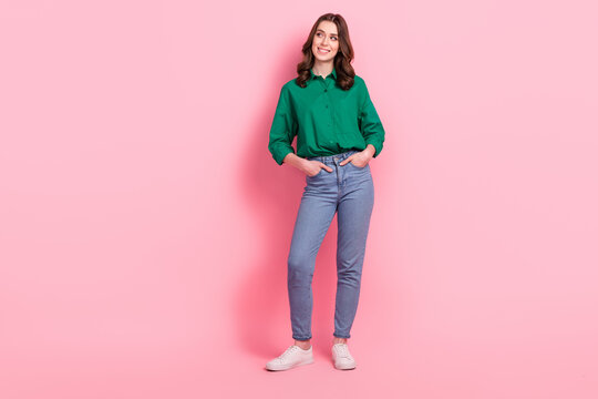 Full size photo of good mood funny girl dressed green shirt hold arms in pockets look at discount empty space isolated on pink background