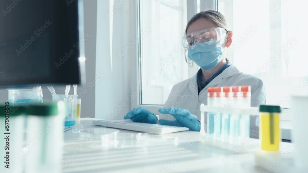 Poster a female researcher sits at a workplace in a laboratory, behind a personal computer monitor. against
