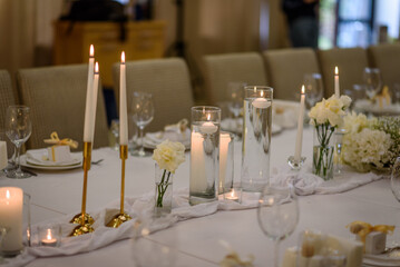 Festive table decorated composition flowers and candles in party area. Table setting, serving closeup. Wedding setup detail. Banquet decoration in hall restaurant. Luxury reception.