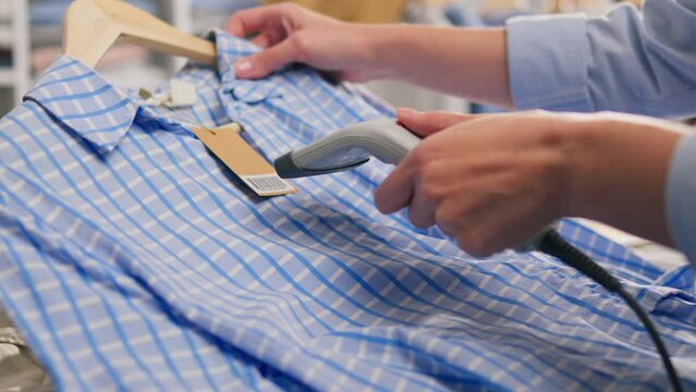 A shopper uses an RFID reader to scan a tag on a new piece of clothing in a fashion store. The reader displays product information including materials used, available sizes and price
