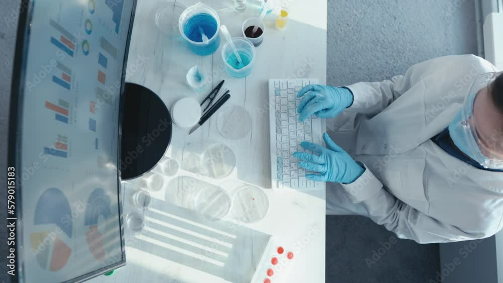 Poster a female researcher sits at a workplace in a laboratory, behind a personal computer monitor. against