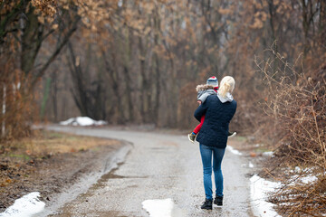 Mother with child walking by rural road in forest