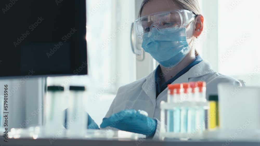 Poster a female researcher sits at a workplace in a laboratory, behind a personal computer monitor. against