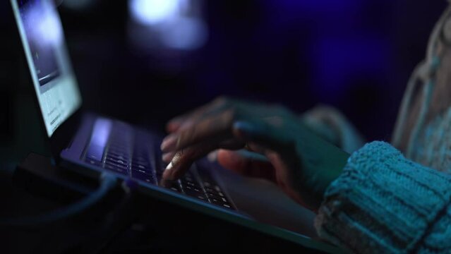 Close up of unrecognizable black woman hands typing on a laptop, dark background. Copy space.
