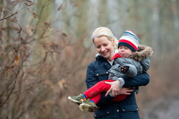 Mother with child walking by rural road in forest