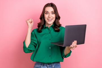 Portrait of delighted person raise fist hold netbook achievement luck isolated on pink color background