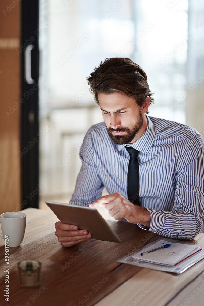 Poster hes a tech savvy exec. a young businessman using a digital tablet in an office.