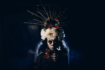 Woman with mexican skull halloween makeup on face. Day of the dead aka Dia de los Muertos and halloween concept.