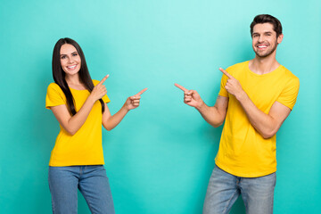 Photo of cute cheerful married couple wear yellow t-shirts showing fingers empty space isolated teal color background