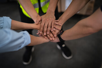 Close up view of warehouse workers putting their hands together. Stack of hands. Unity and teamwork.