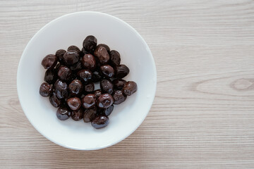 Black olives berries in white cup source of healthy polyunsaturated and saturated fats