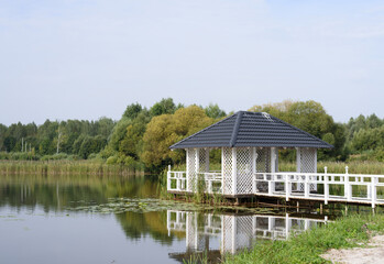 Obraz premium Wooden gazebo with pier on lake