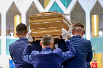 Undertakers carry a coffin to the church altar for the funeral
