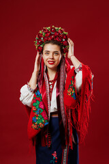 Portrait of ukrainian woman in traditional ethnic clothing and floral red wreath on viva magenta studio background. Ukrainian national embroidered dress call vyshyvanka. Pray for Ukraine