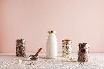 seed milk in bottle on beige background with chia, flax, sunflower, sesame seed. Raw diet meal....
