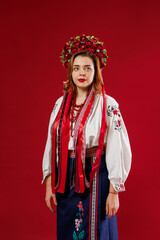 Portrait of ukrainian woman in traditional ethnic clothing and floral red wreath on viva magenta studio background. Ukrainian national embroidered dress call vyshyvanka. Pray for Ukraine