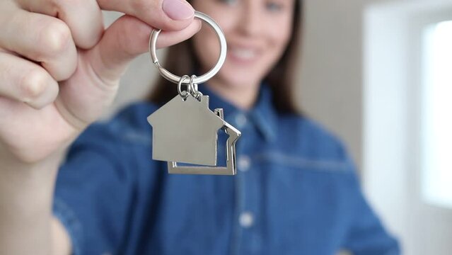 Focus on bunch of keys from house flat apartment in hand of smiling woman showing bunch of keys. Housewarming, moving to a new apartment.