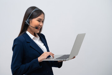 Beautiful Asian call center operator talking with customer using laptop isolated on grey background.