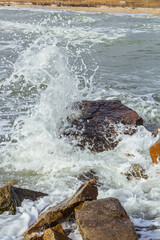 A shot of the sea surf. Splashes of water hitting the stone. Ocean surf among the rocks. Background of the tide.