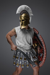 Shot of antique greek soldier with golden helmet holding rounded shield and gladius.