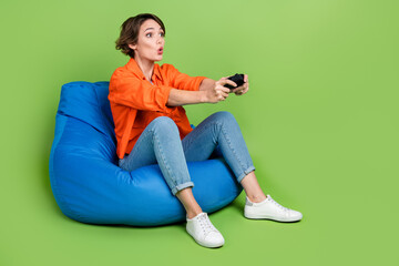 Obraz na płótnie Canvas Full length photo of impressed sweet woman wear denim jacket bean bag playstation empty space isolated green color background