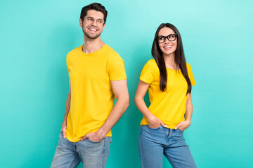 Fototapeta premium Photo of two teammates partners yellow t-shirts denim jeans hands pockets stylish ray ban glasses good job isolated on aquamarine color background