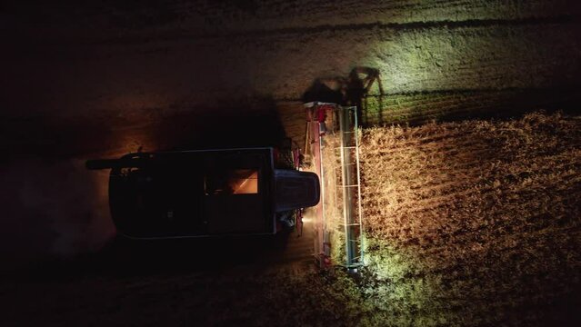 Aerial Shot At Night Harvester Gathering Crops From Agricultural Fields. Global Food Crisis And Grain Supply Chains