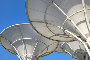 Low angle view huge canopies tensile membrane structure against sunny blue sky. - obrazy, fototapety, plakaty