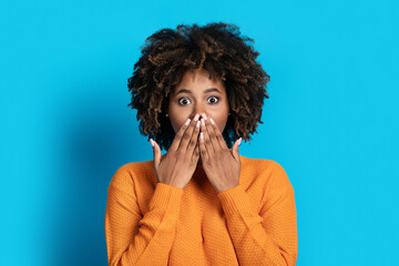 Surprised emotional young black woman cover mouth looking at camera