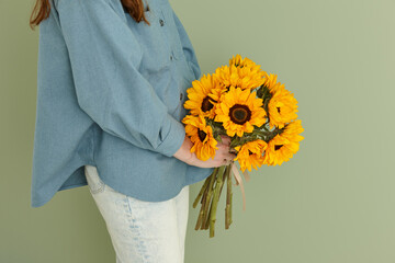 Woman with a summer bunch of sunflowers on green wall background