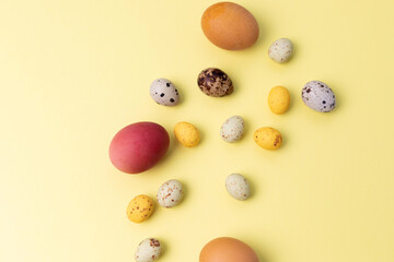 Colored eggs of different sizes on a yellow background. Symbol of the Easter holiday. Easter background. Flat lay