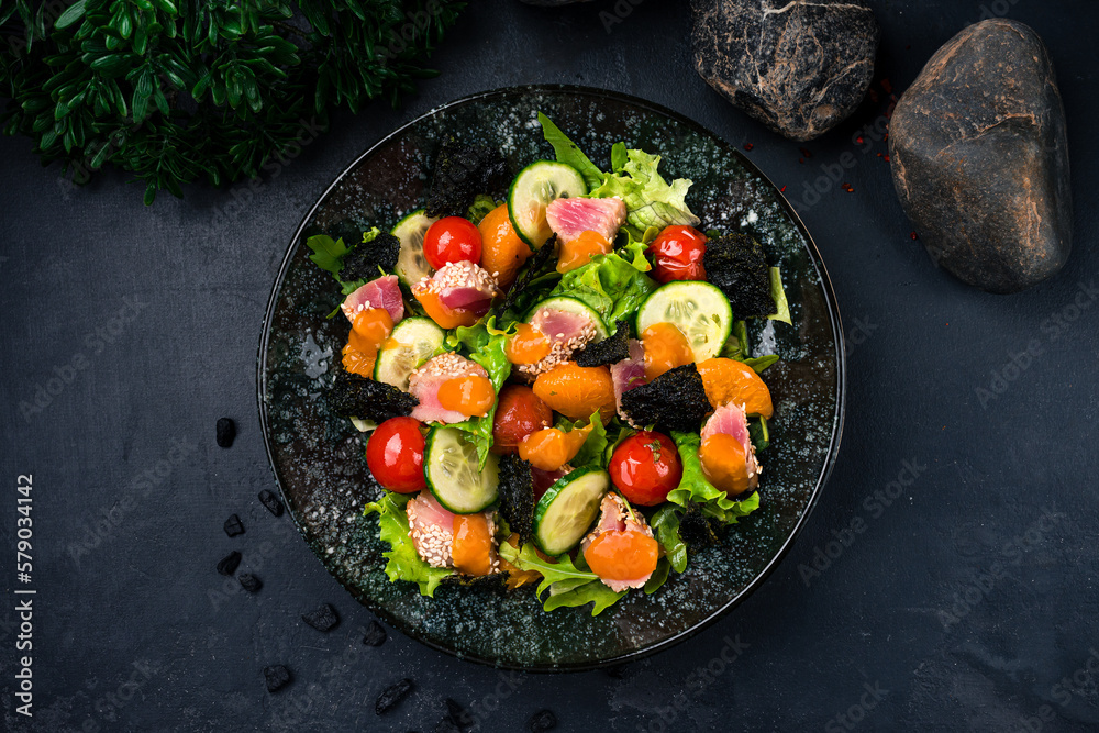 Canvas Prints Fresh salad with tuna, lettuce, tomatoes, cucumbers, arugula, nori, tangerines, sesame and mango sauce on a plate.