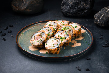 Hot sushi rolls with salmon, eel and cream cheese on a plate.