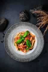 Traditional Italian Penne pasta in tomato sauce with salami, feta cheese, pepper and basil.