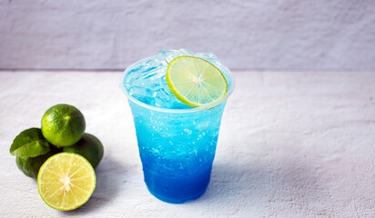 Blue Hawaiian drink in a plastic glass and lime on white background