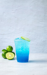 Blue Hawaiian drink in a plastic glass and lime on white background
