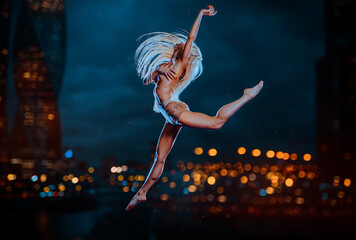 Young blond woman jumping on city background at twilight