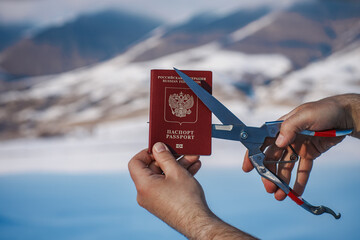 Man cutting Russian passport on mountains background, immigration concept