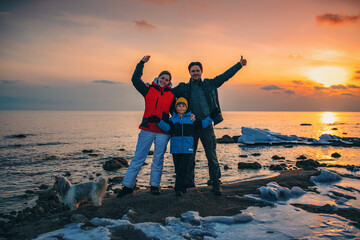 Fototapeta premium Father, mother, son and dog happy family posing on lake sunset background at winter season