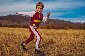 Child running on autumn field on mountains background