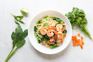Fried rice with shrimp has vegetable in plate on white table.