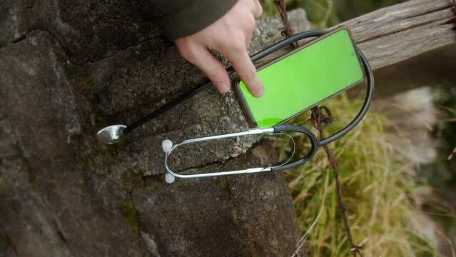Using Digital Health Apps: Hand Operating Smartphone with Stethoscope Wrapped Around It