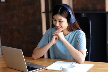 Young asian girl studying at home. University Women student learn and research from internet and take a note by e-learning program.