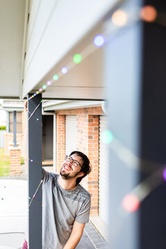 Man putting up smart led Christmas lights on front of home