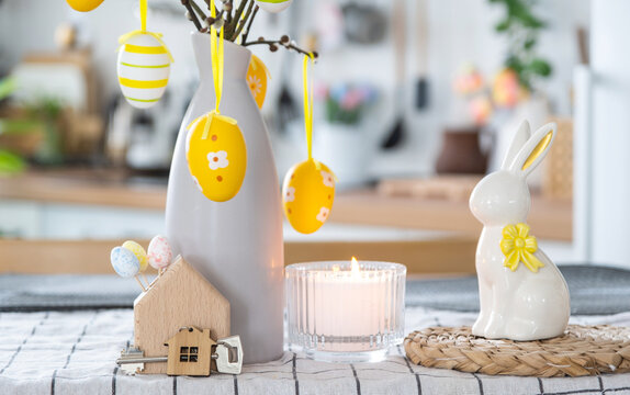 Key to house of cozy home with Easter decor with rabbit and eggs on table of kitchen. Building, design, project, moving to new house, mortgage, insurance, rent and purchase real estate