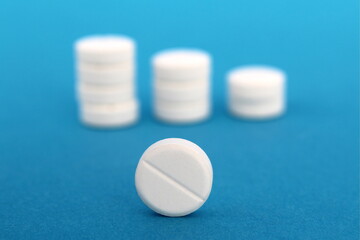 Several small stacks of pills stand on a blue background.